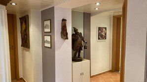 A hallway with artwork on the walls, a statue, and a cabinet. - Fe apartm., in a quiet location, 5 minut. from the S-Bahn + Regio train station (Meckesheim)