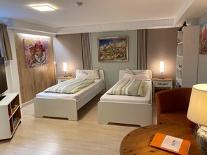 A hotel room with two beds, a desk, a chair, and a TV. - Fe apartm., in a quiet location, 5 minut. from the S-Bahn + Regio train station (Meckesheim)