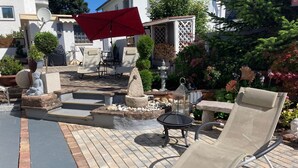 A patio with a stone fire pit, a red umbrella, and outdoor furniture. - Fe apartm., in a quiet location, 5 minut. from the S-Bahn + Regio train station (Meckesheim)