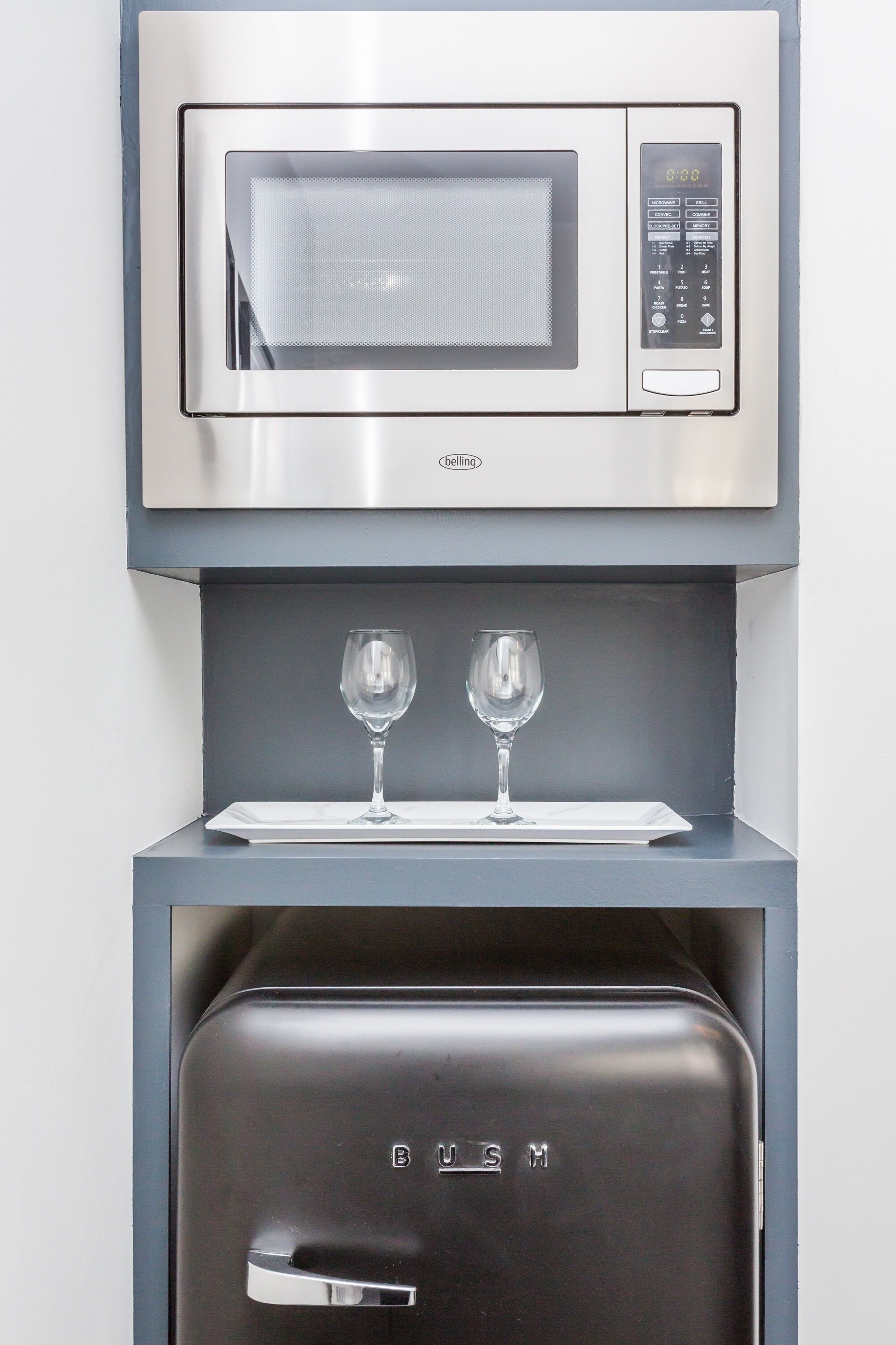 Een moderne keuken met een ingebouwde magnetron en een zwarte koelkast.