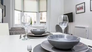 A dining table set with a bowl, two wine glasses, and cutlery. - Studio In the Lanes (Brighton)