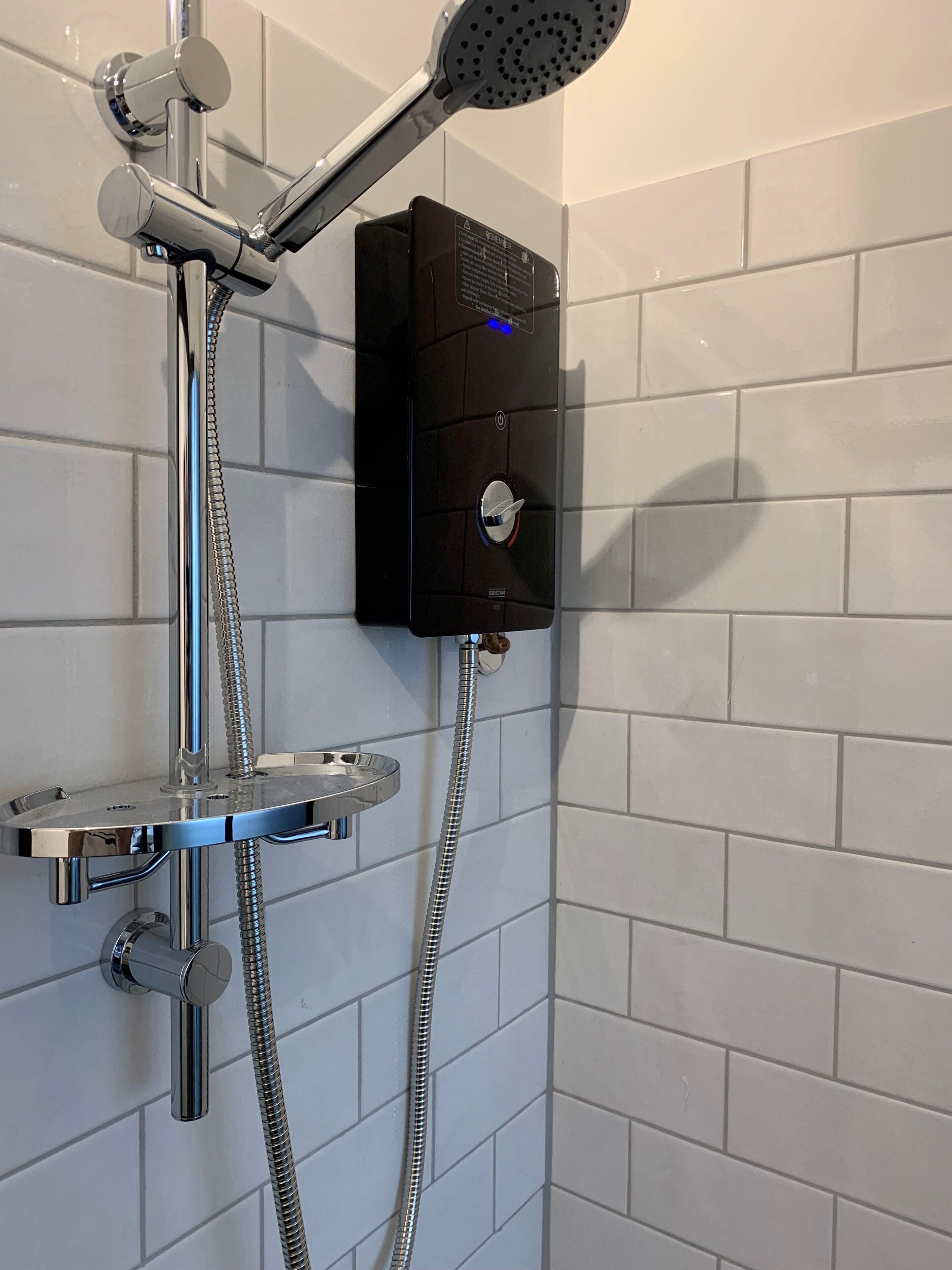 A modern shower with a handheld showerhead, a fixed showerhead, and a control panel with a digital display.