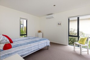 A bedroom with a bed, a chair, a nightstand, and a window.