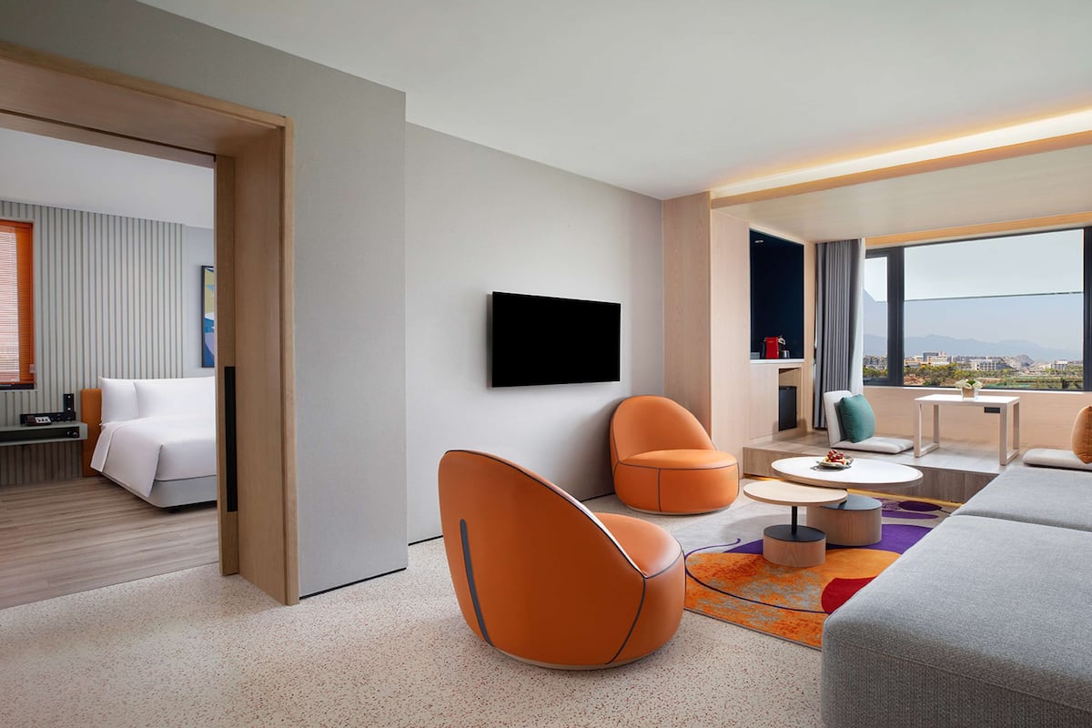 Une chambre d’hôtel moderne équipée d’un lit, d’un coin salon, d’une télévision et offrant une vue sur la ville.