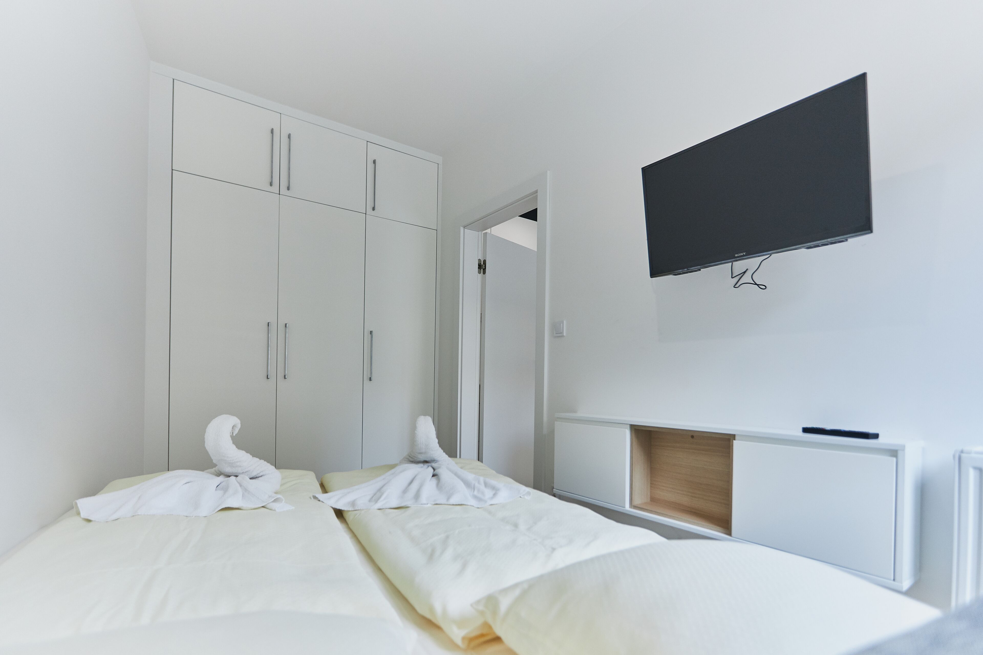 Ein Hotelzimmer mit Bett, Wandfernseher und Kleiderschrank.