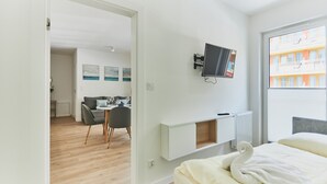 A modern hotel room with a bed, a desk, and a TV mounted on the wall. - Apartamenty Swinoujscie – Lissa (Swinoujscie)