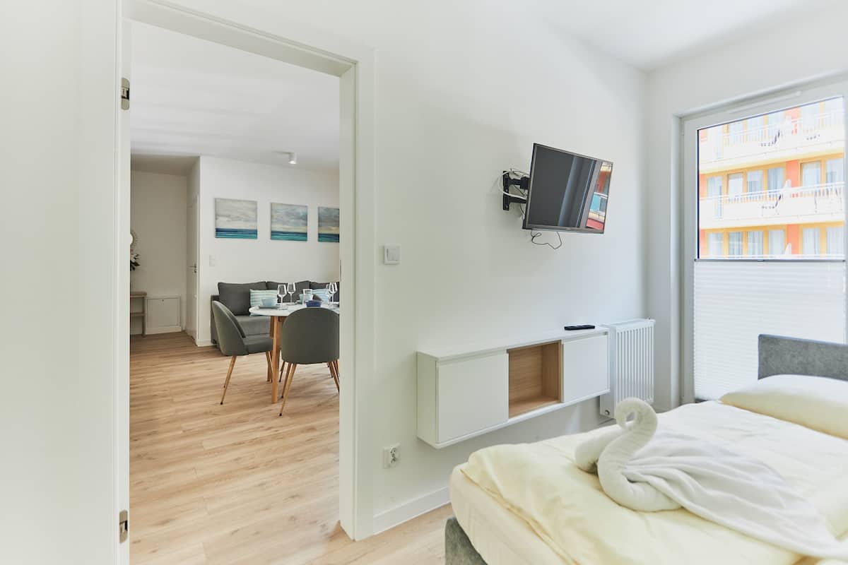 A modern hotel room with a bed, a desk, and a TV mounted on the wall.