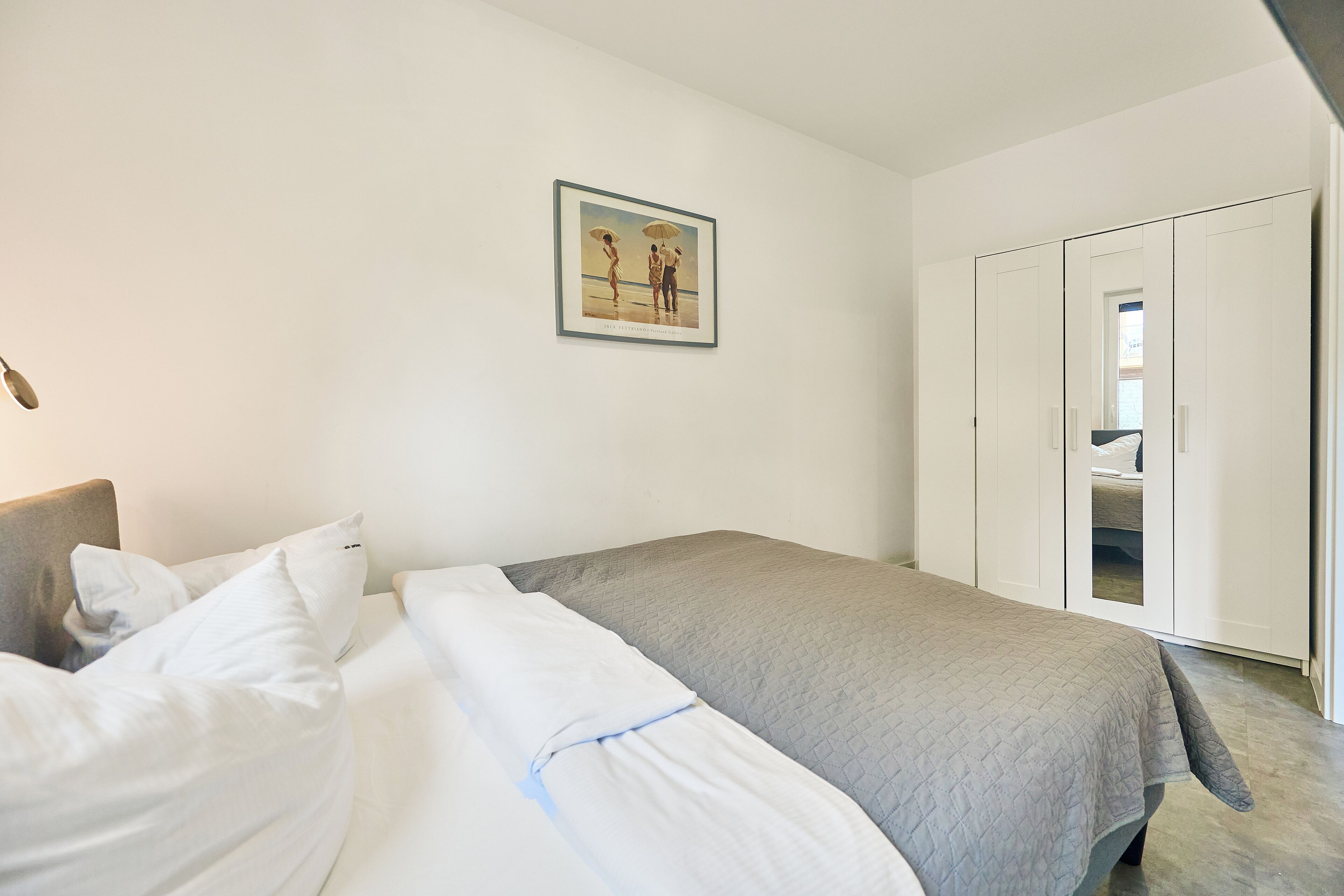 A bedroom with a bed, a wardrobe, and a framed picture on the wall.