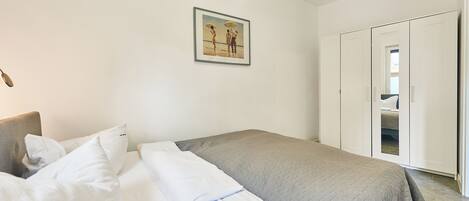 A bedroom with a bed, a wardrobe, and a framed picture on the wall.