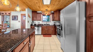 A modern kitchen with wooden cabinets, stainless steel appliances, and a granite countertop. - Upscale Home With Expansive Mountain Views (Banner Elk)