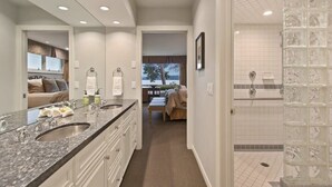 Une salle de bain moderne dotée d’un meuble-lavabo à deux vasques, d’une douche à parois de verre et offrant une vue sur l’extérieur.