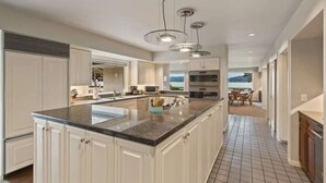 Une cuisine moderne avec des meubles blancs, un plan de travail en granit et des luminaires suspendus.