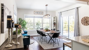A modern kitchen with a dining area, large windows, and a chandelier.