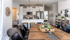 A modern kitchen with white cabinets, stainless steel appliances, and hanging pendant lights.