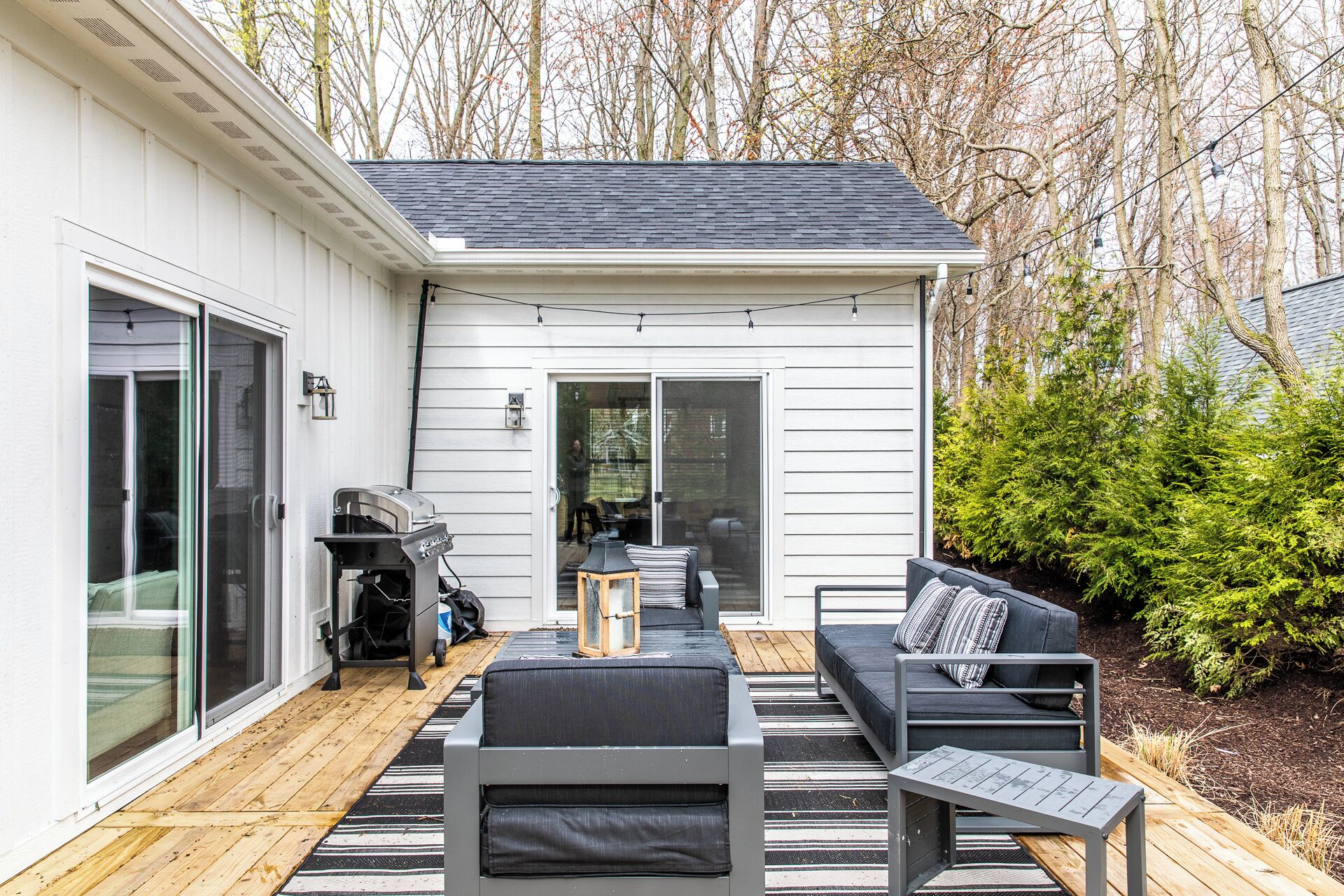 Un patio con mobiliario exterior, una parrilla y una puerta corrediza que da a una terraza.