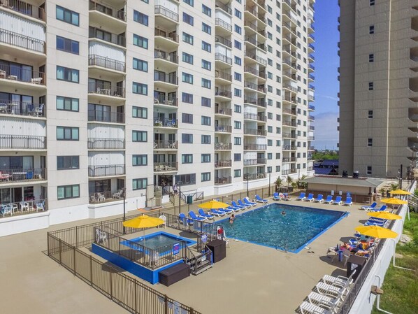Un hôtel de grande hauteur doté d’une piscine sur le toit, de nombreux balcons et d’un espace extérieur aménagé pour s’asseoir.