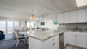 Une cuisine moderne avec des armoires blanches, un plan de travail en marbre et des luminaires suspendus.