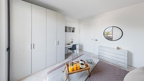 Ein modernes Schlafzimmer mit großem Kleiderschrank, Schreibtisch und Nachttisch mit einem Frühstücksbrettchen.