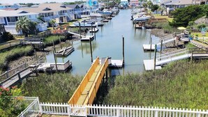 A marina with docked boats, a wooden bridge, and residential buildings in the background. - Cozy 3BR oceanfront home in Holden Beach, perfect for family getaways. (Holden Beach)