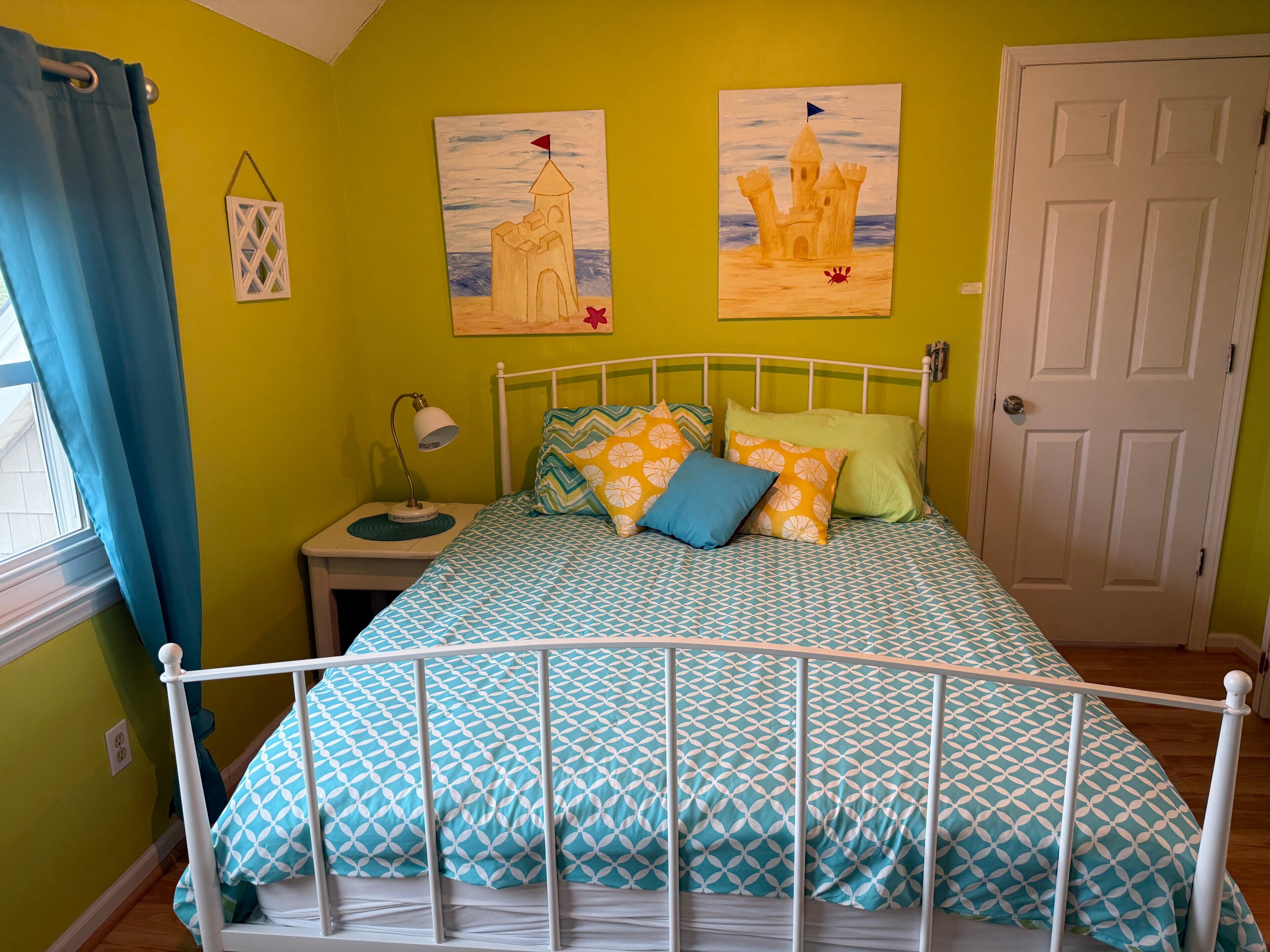 A bedroom with a bed, a nightstand, a lamp, and a door.
