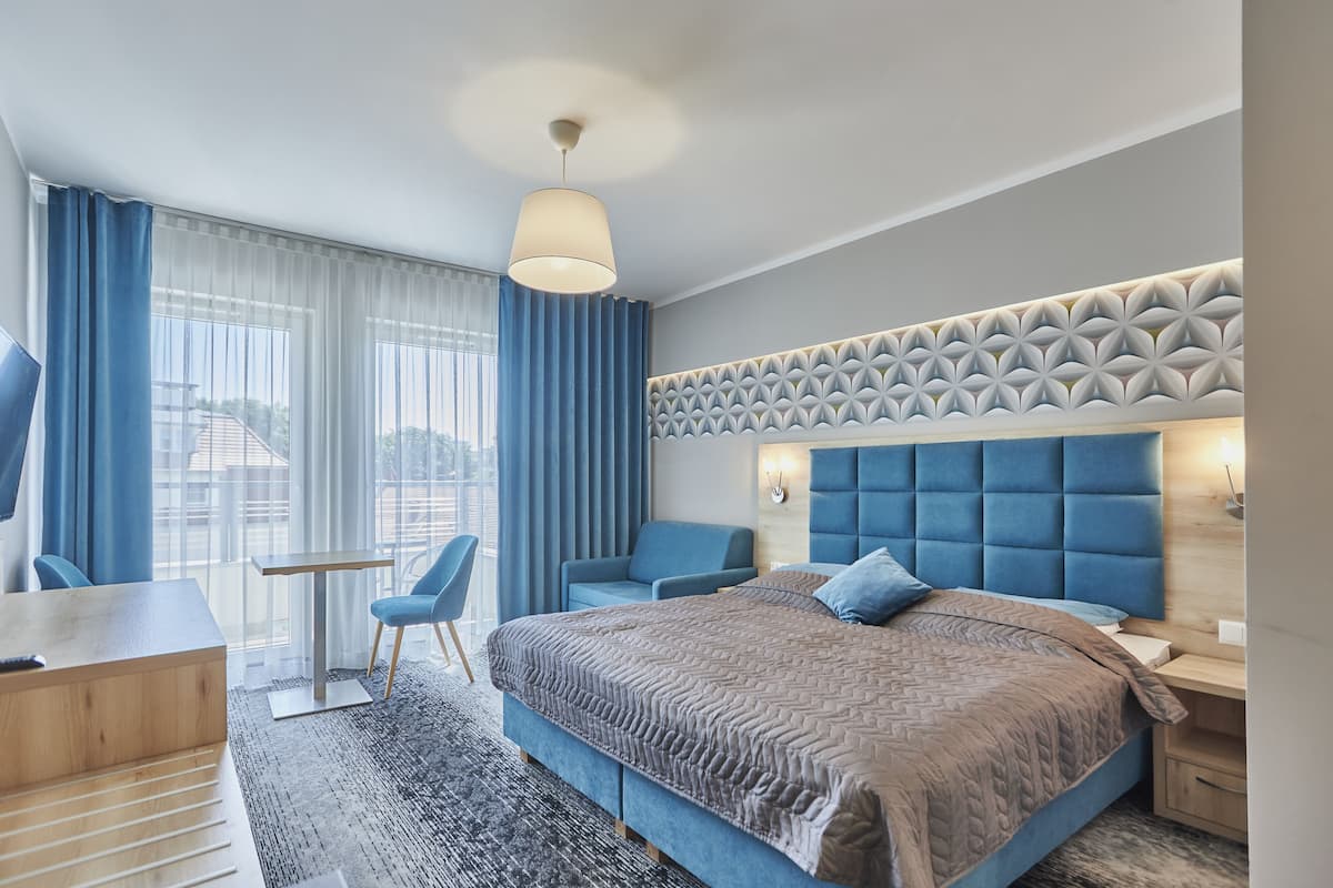 Ein modernes Hotelzimmer mit einem großen Bett, einem Schreibtisch, einem Stuhl und Blick ins Freie.