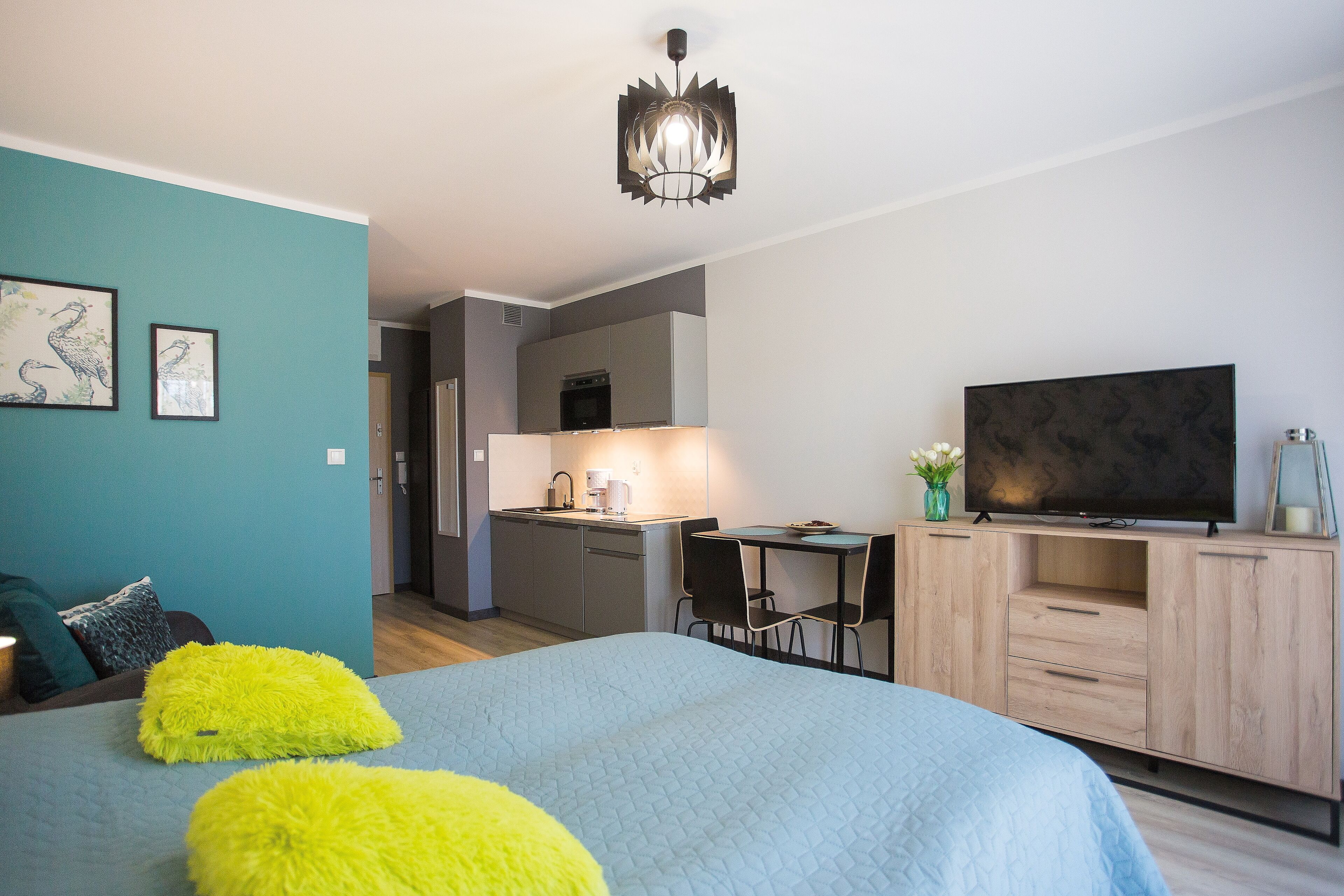 A modern bedroom with a large bed, a desk, and a television.