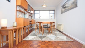 A dining area with a wooden table and chairs, a bookshelf, and a radiator. - Sea Breeze, Selsey -  a town house that sleeps 6 guests  in 3 bedrooms (Chichester)