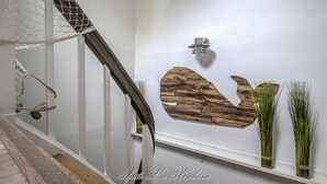 Una escalera con barandilla de madera, un aplique de pared y detalles decorativos en la pared.
