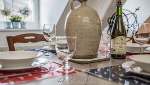 Una mesa de comedor con una jarrón, una botella de vino y copas.