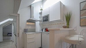 Cocina compacta con armarios blancos, un microondas y un lavamanos pequeño.