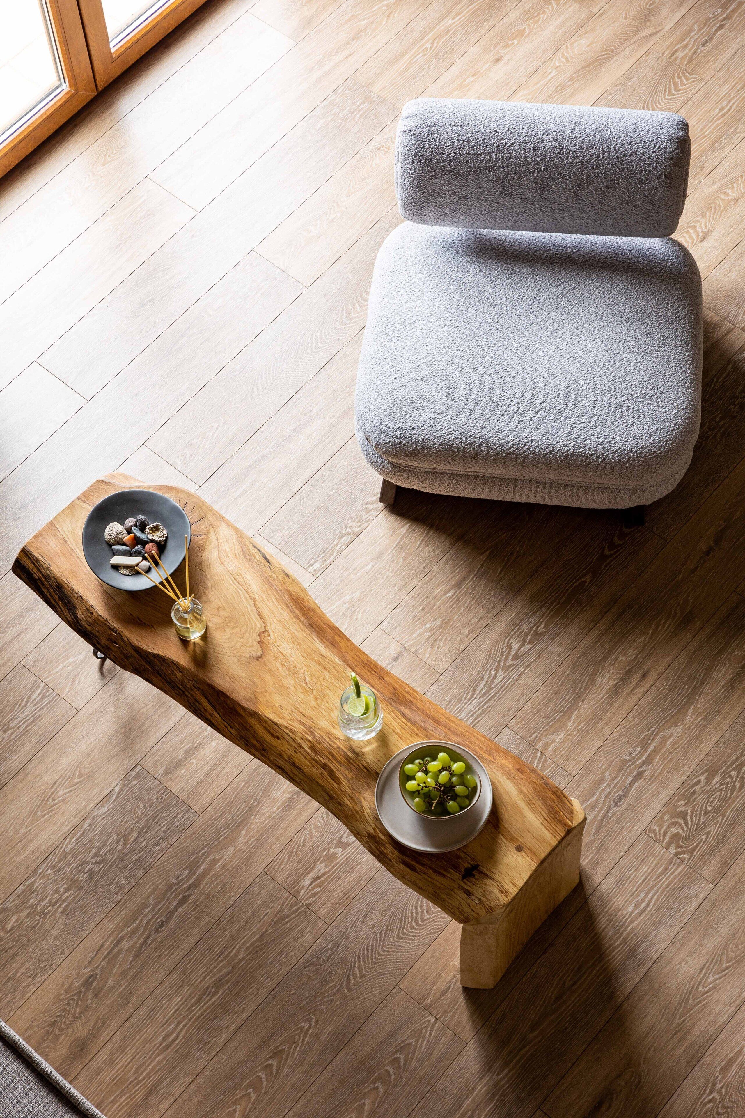 A modern living room with a grey sofa, a wooden coffee table with decorative items, and a wooden floor.