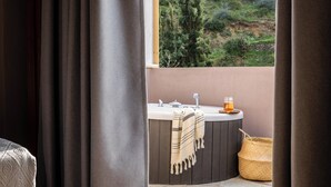 A bathroom with a bathtub, a sink, and a window overlooking a hillside. - Avaton Suites & Villa Philian Collection (Skiathos)