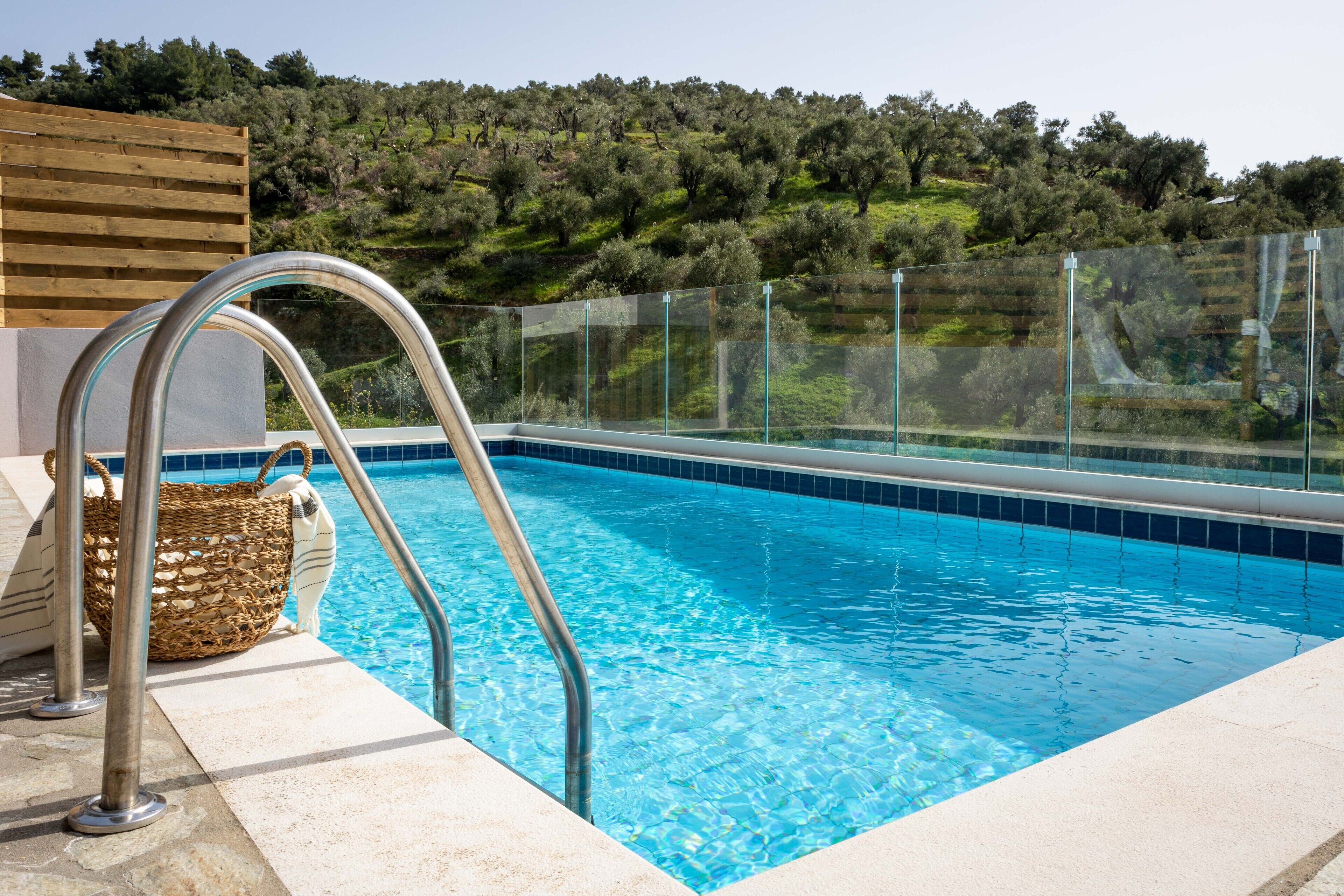 A swimming pool with clear blue water, a metal ladder, and a wicker basket on the edge.