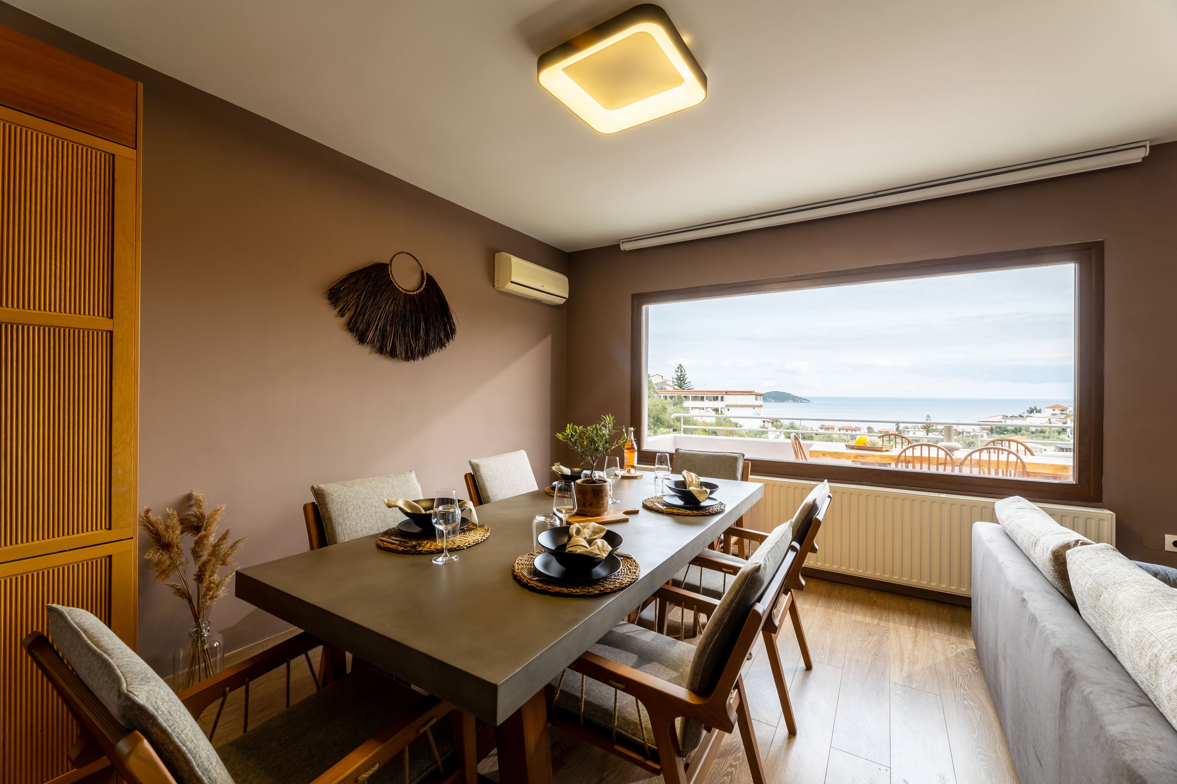 A dining area with a large table, chairs, and a view of the sea.