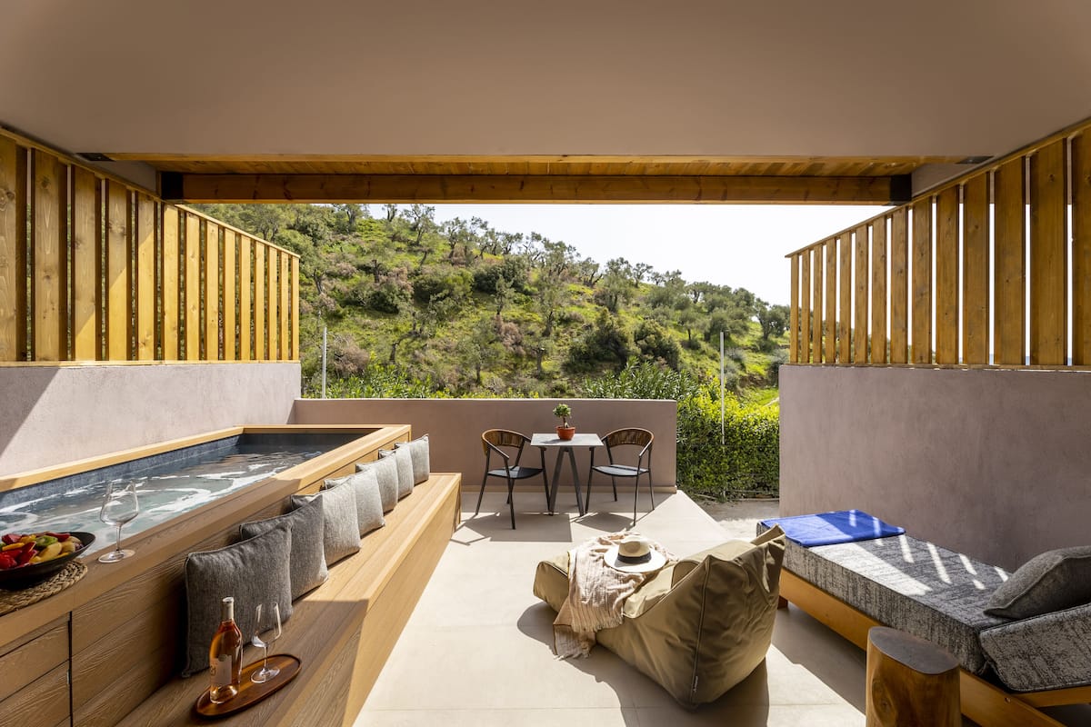 Un patio exterior moderno con hidromasaje, zona de estar y una mesa con sillas.