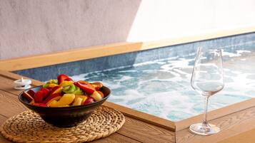 Ein Holztisch mit Obstschale und einem Glas Wasser in der Nähe eines Whirlpools.
