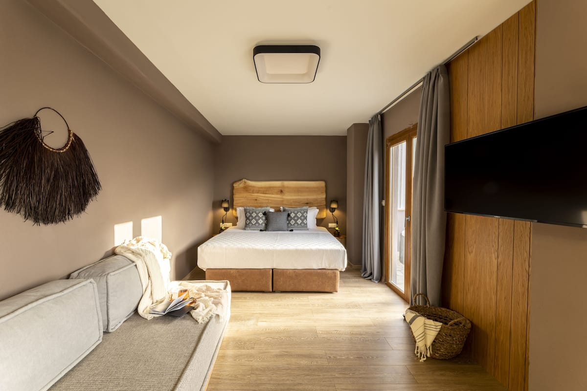 Un dormitorio con una cama grande, un sofá, un televisor y un cabecero de madera.