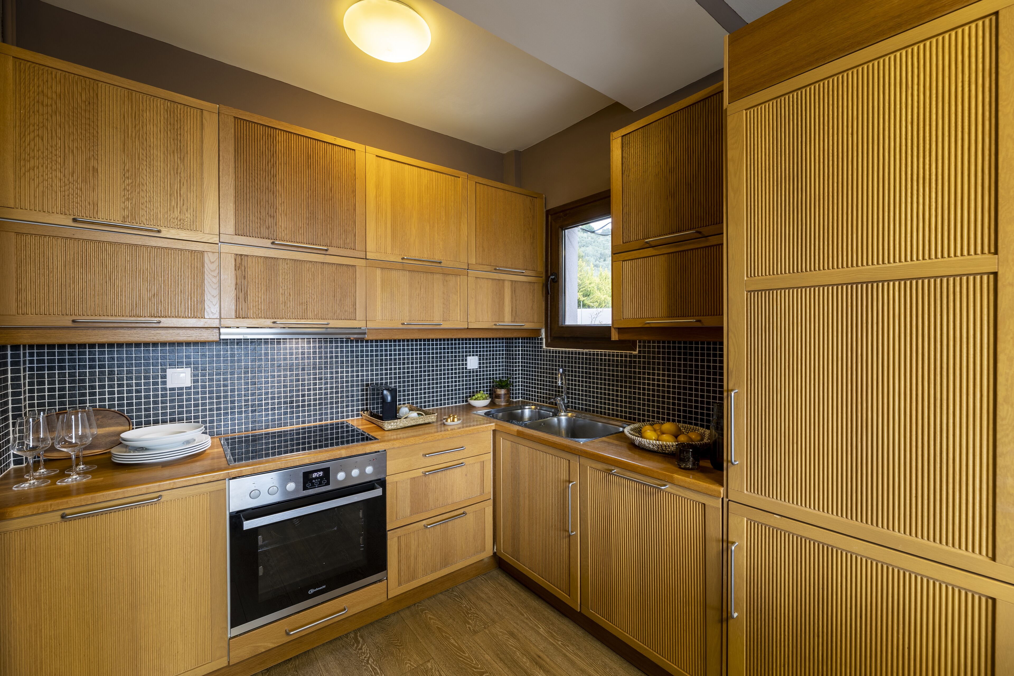 A kitchen with wooden cabinets, a black oven, a sink, and a window.