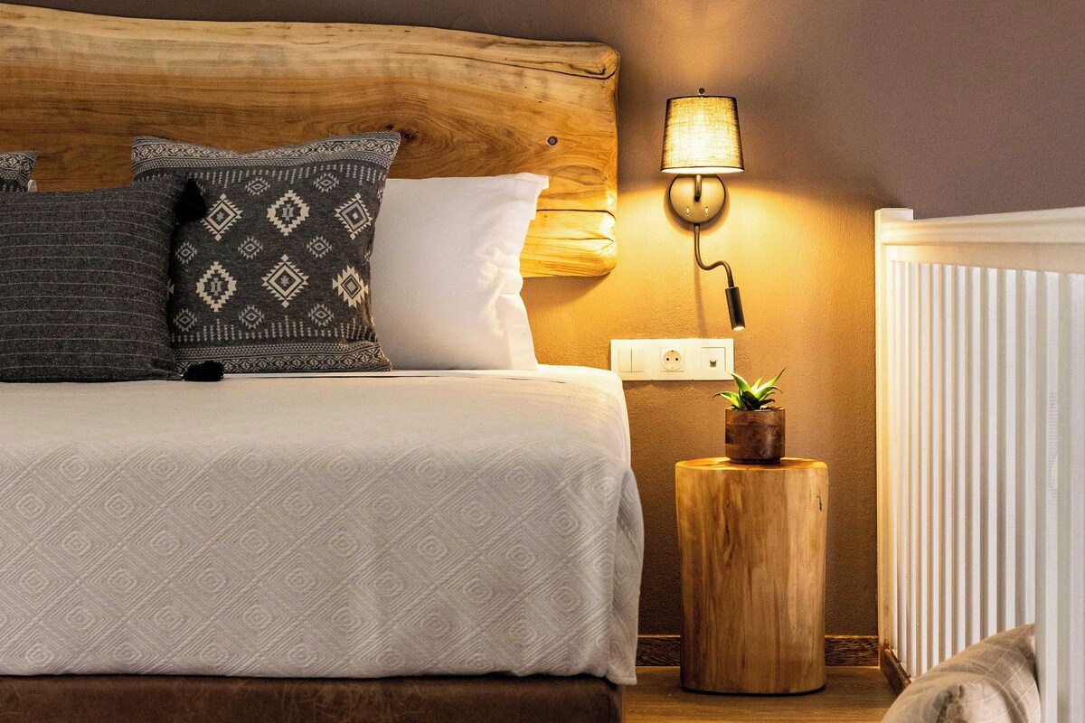 A bedroom with a wooden headboard, a bedside lamp, a small wooden nightstand, and a wicker basket.