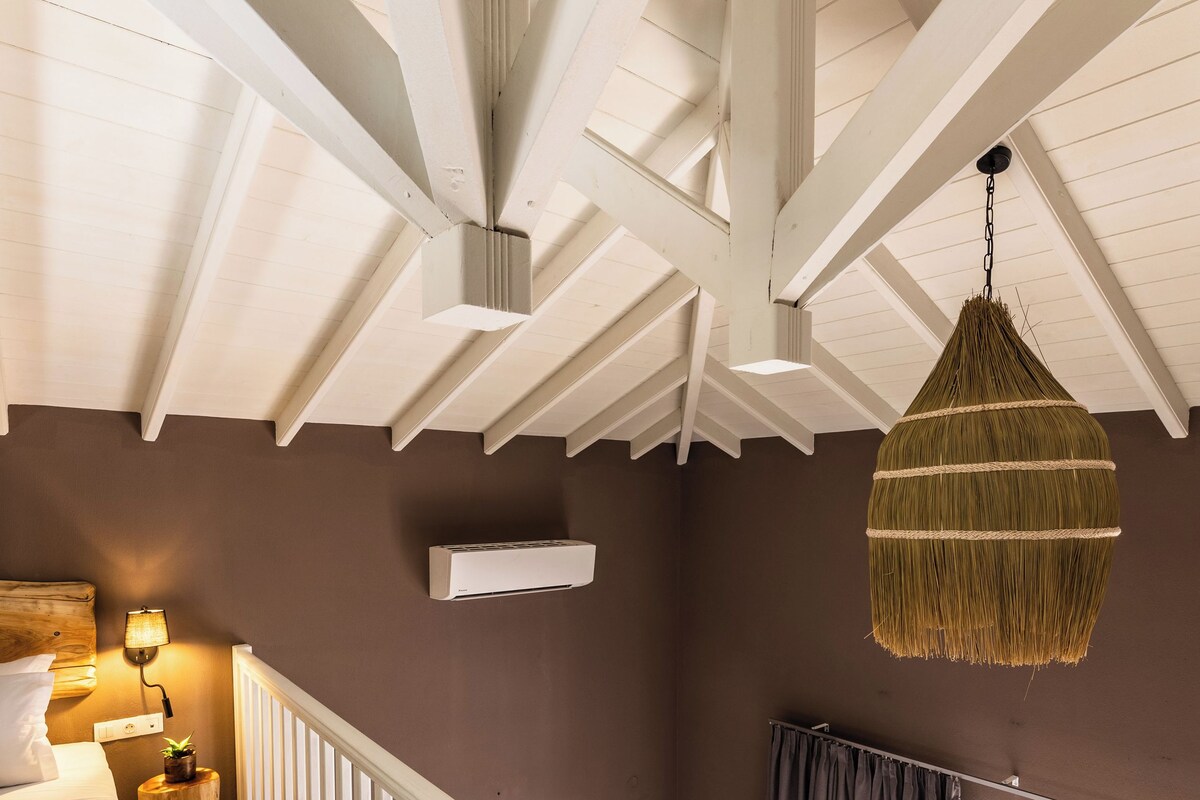 A bedroom with a bed, bedside lamp, and a hanging basket.