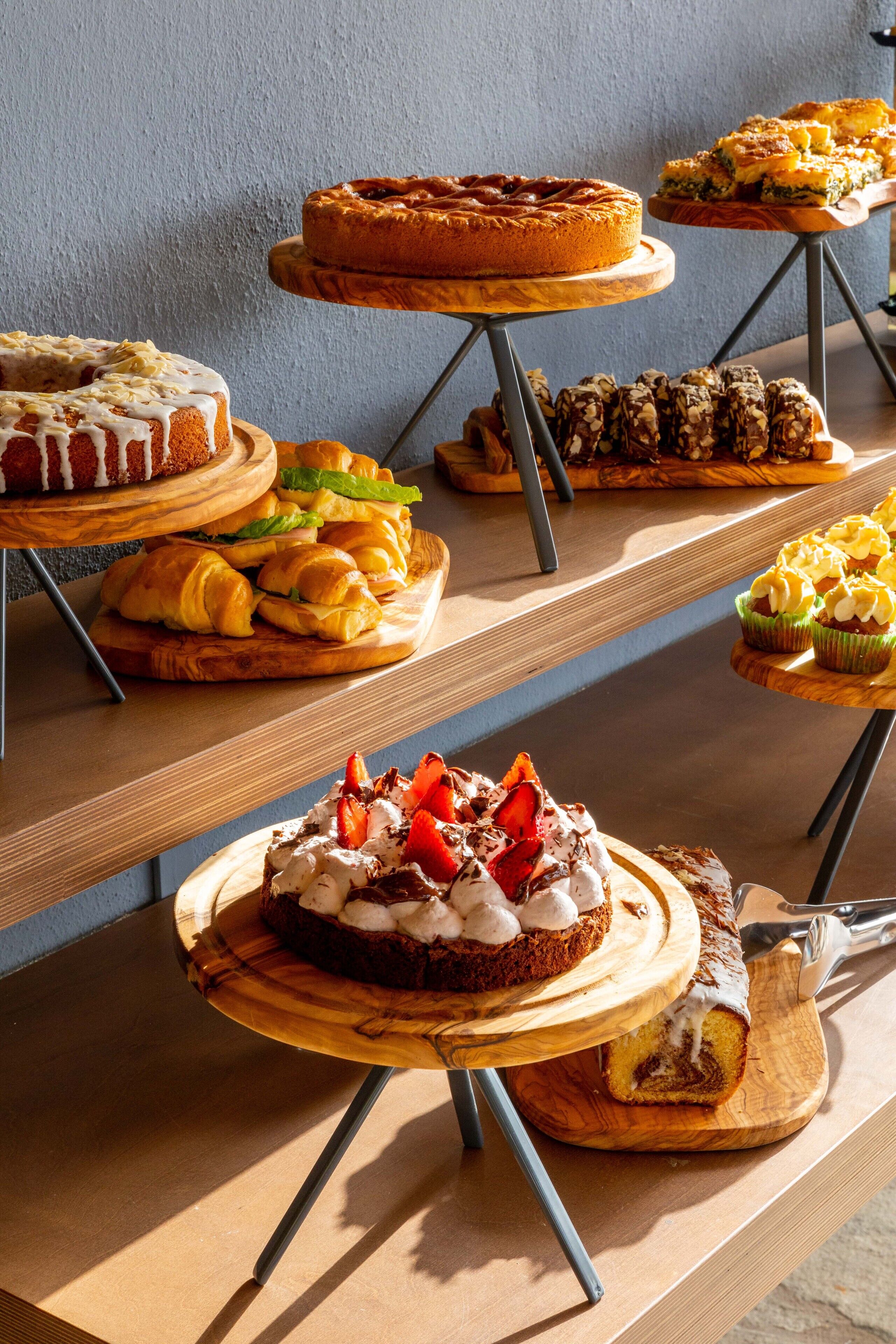 Um buffet com diversos doces e pâtisseries em tábuas de madeira.