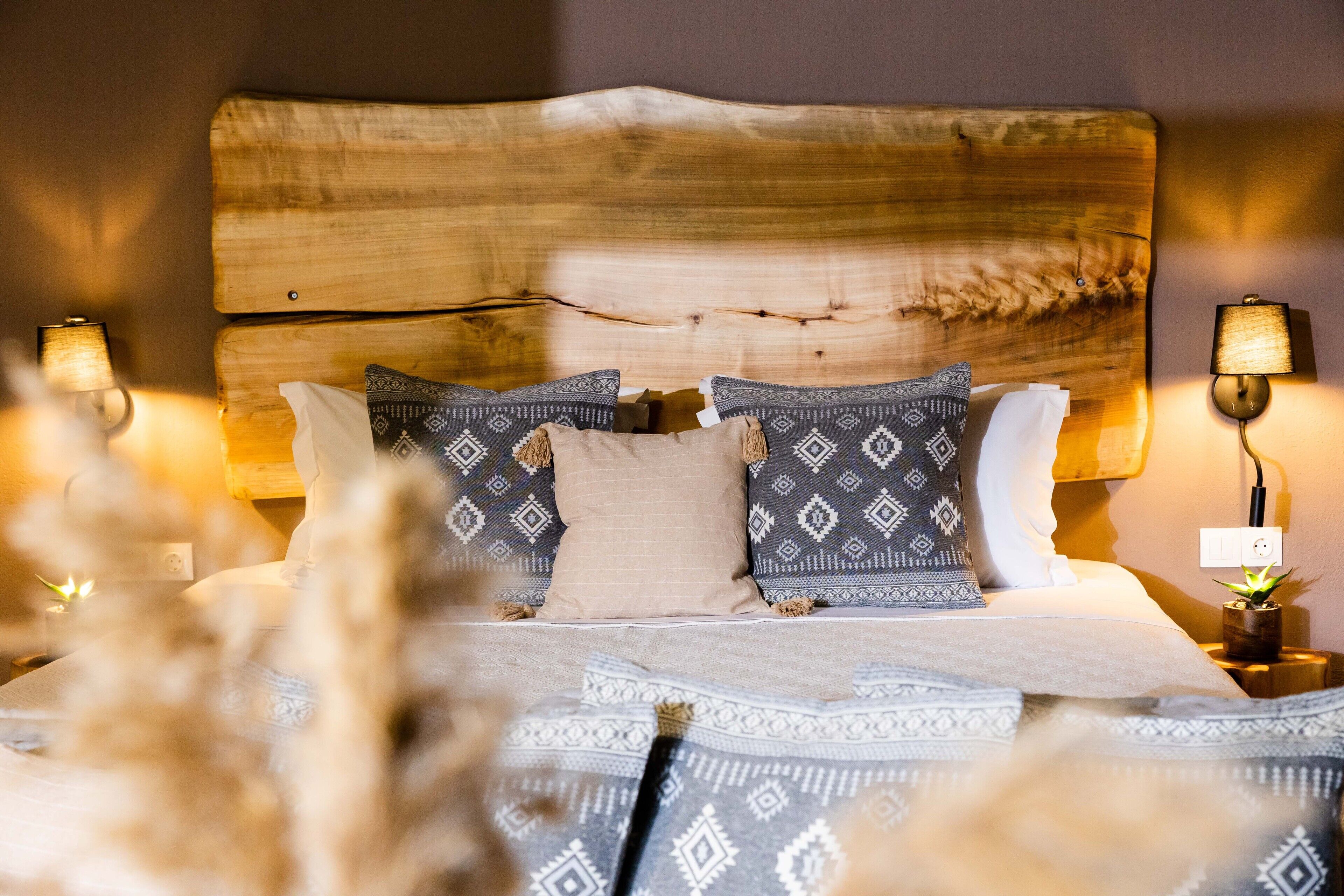 A bed with a wooden headboard, patterned pillows, and bedside lamps.
