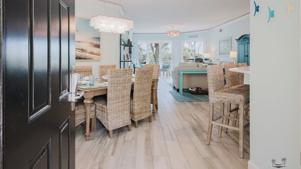 A dining area with wicker chairs and a table, a kitchen with a blue cabinet, and a view of the outdoors.