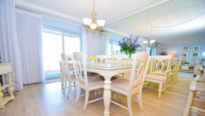 A dining area with a glass table, white chairs, and a chandelier. - Harbour Island 103L-Baywater 14th St, WIFI, Pool, Elev, W/D, AC (Ocean City)