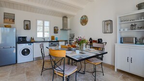 Eine moderne Küche mit Essbereich, ausgestattet mit einem großen Tisch, Stühlen, einer Waschmaschine und einer Mikrowelle.