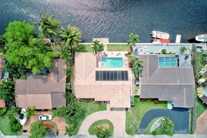An aerial view of a residential area with a swimming pool, solar panels, and a tennis court.