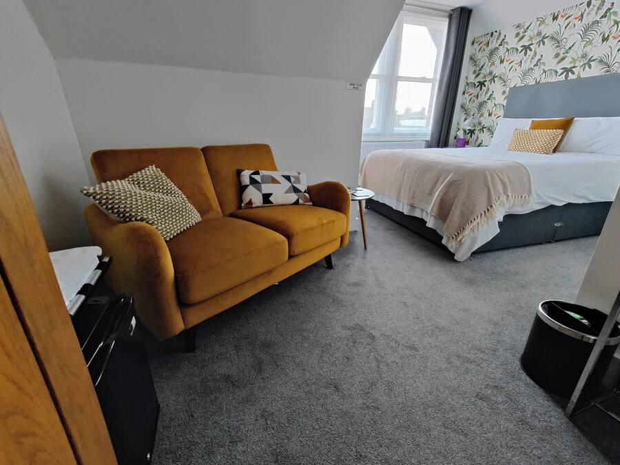 A hotel room with a sofa, a bed, a small table, and a window.