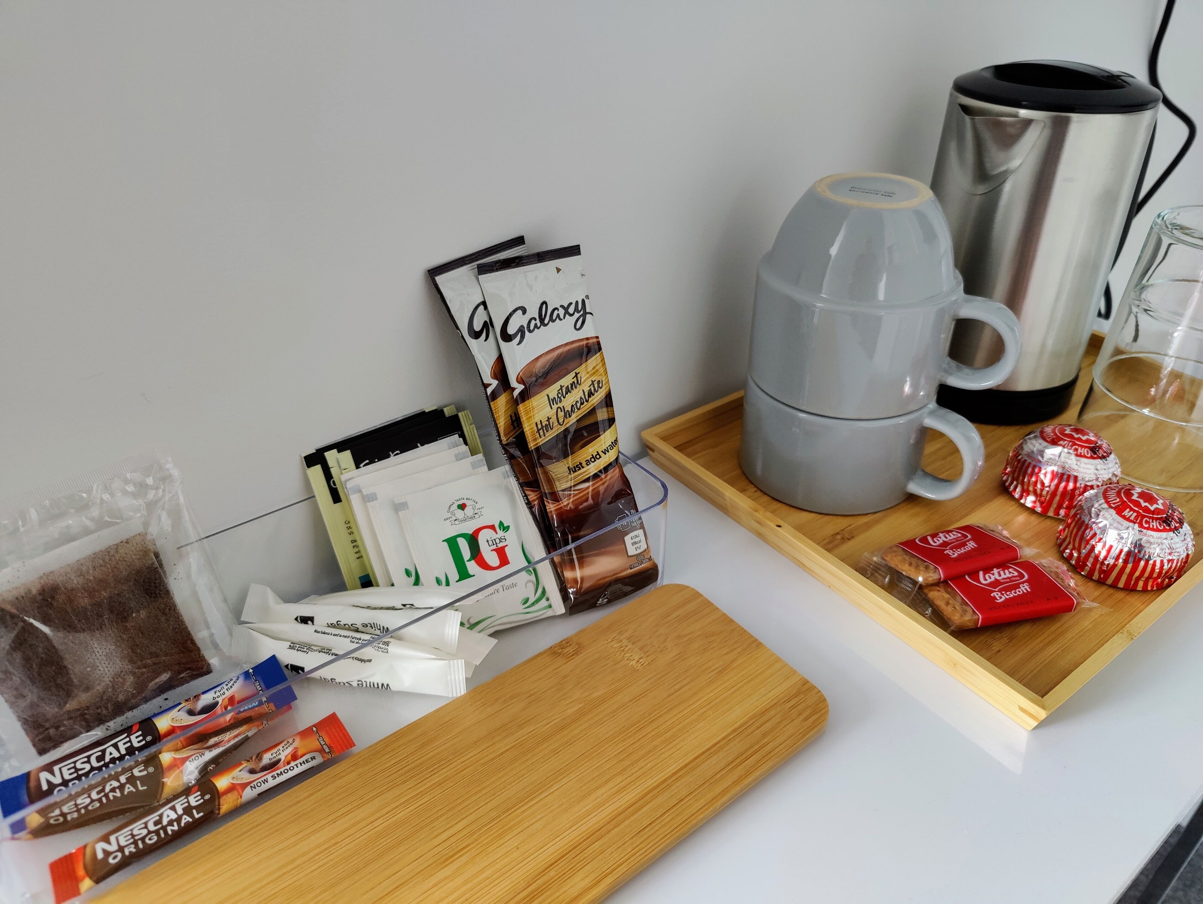 Ein Frühstücksbrett mit Kakaopulver, Nescafe-Kaffeepäckchen und Cantuccini-Keksen.