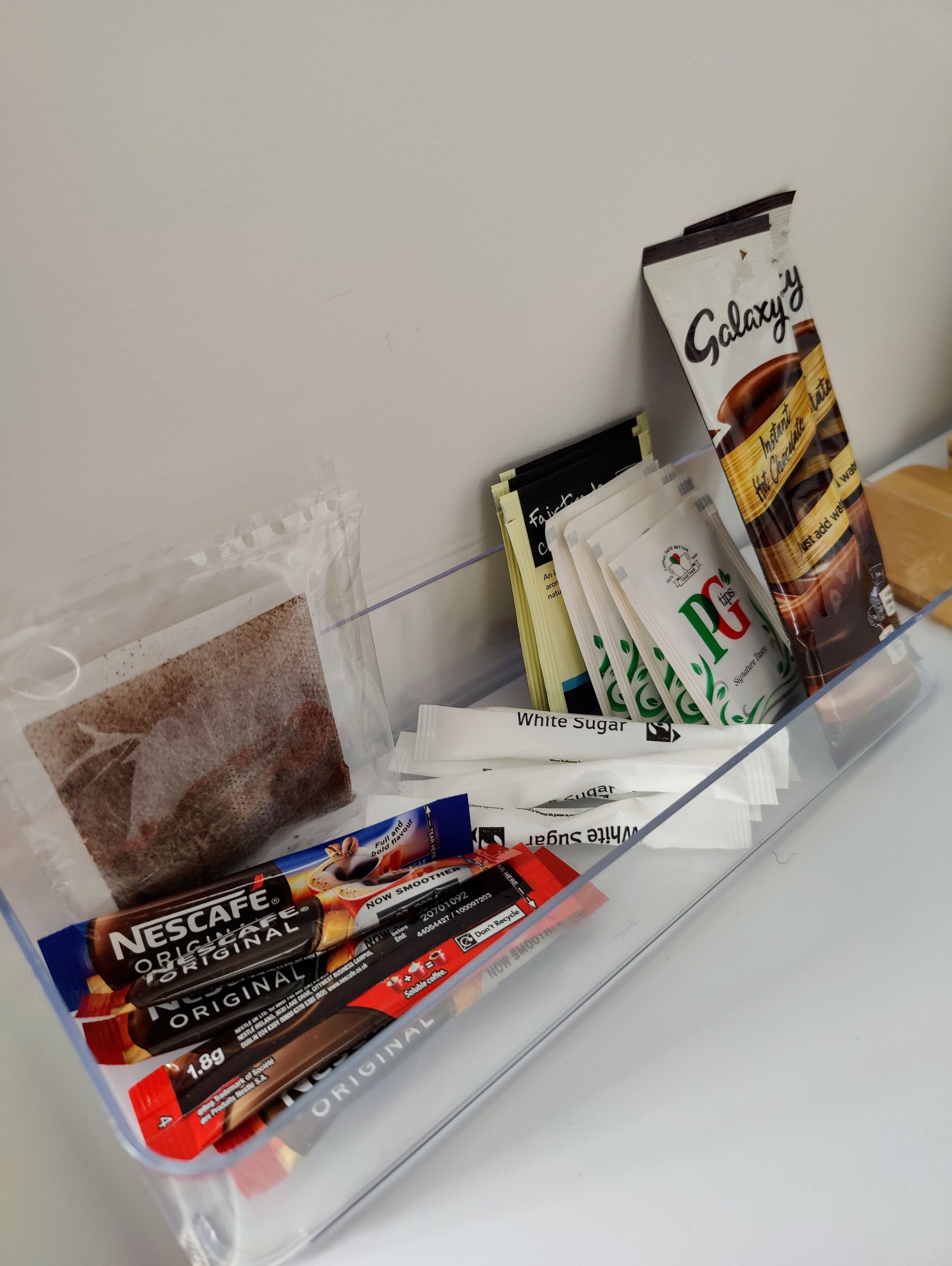 En hylla med olika typer av kaffeprodukter, inklusive Nescafé, Galaxy och vitt socker.
