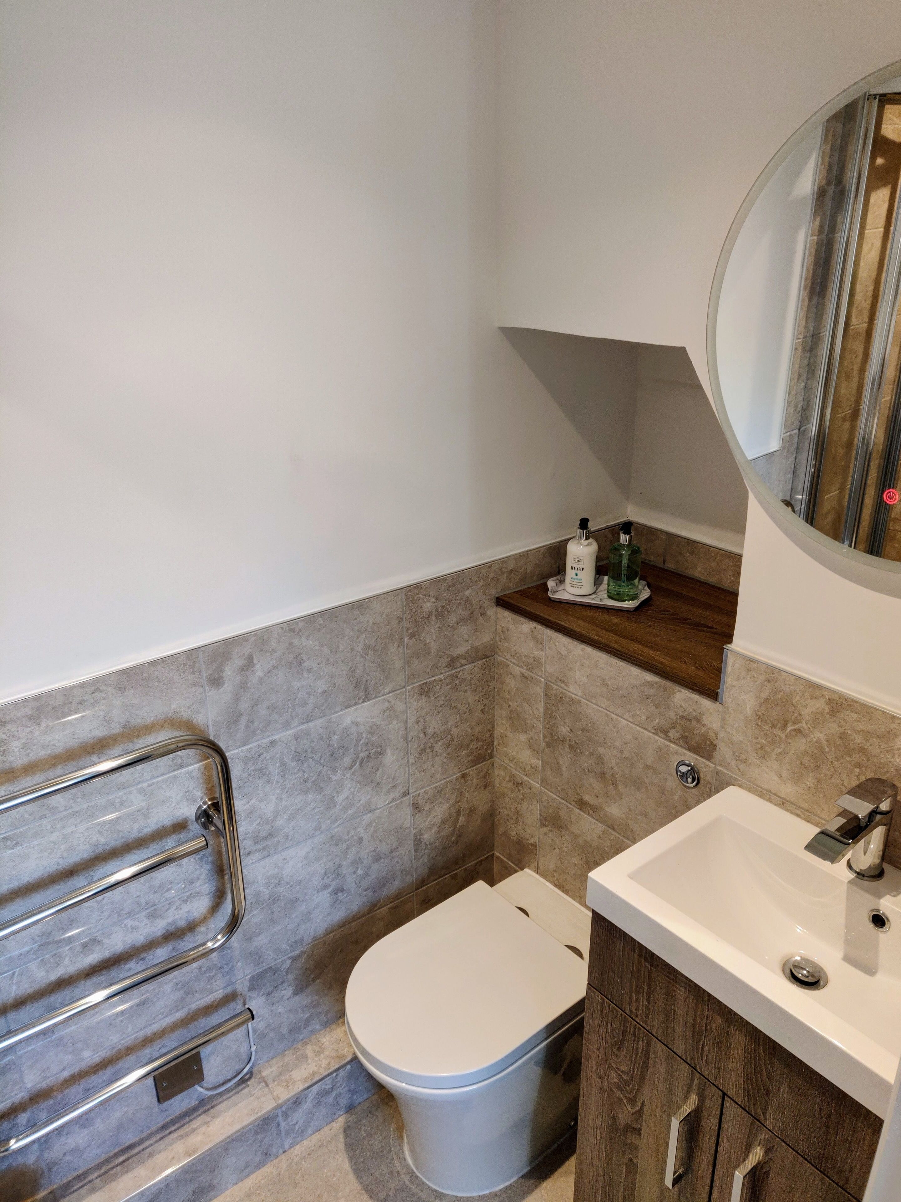 Een moderne badkamer met toilet, wastafel en spiegel.
